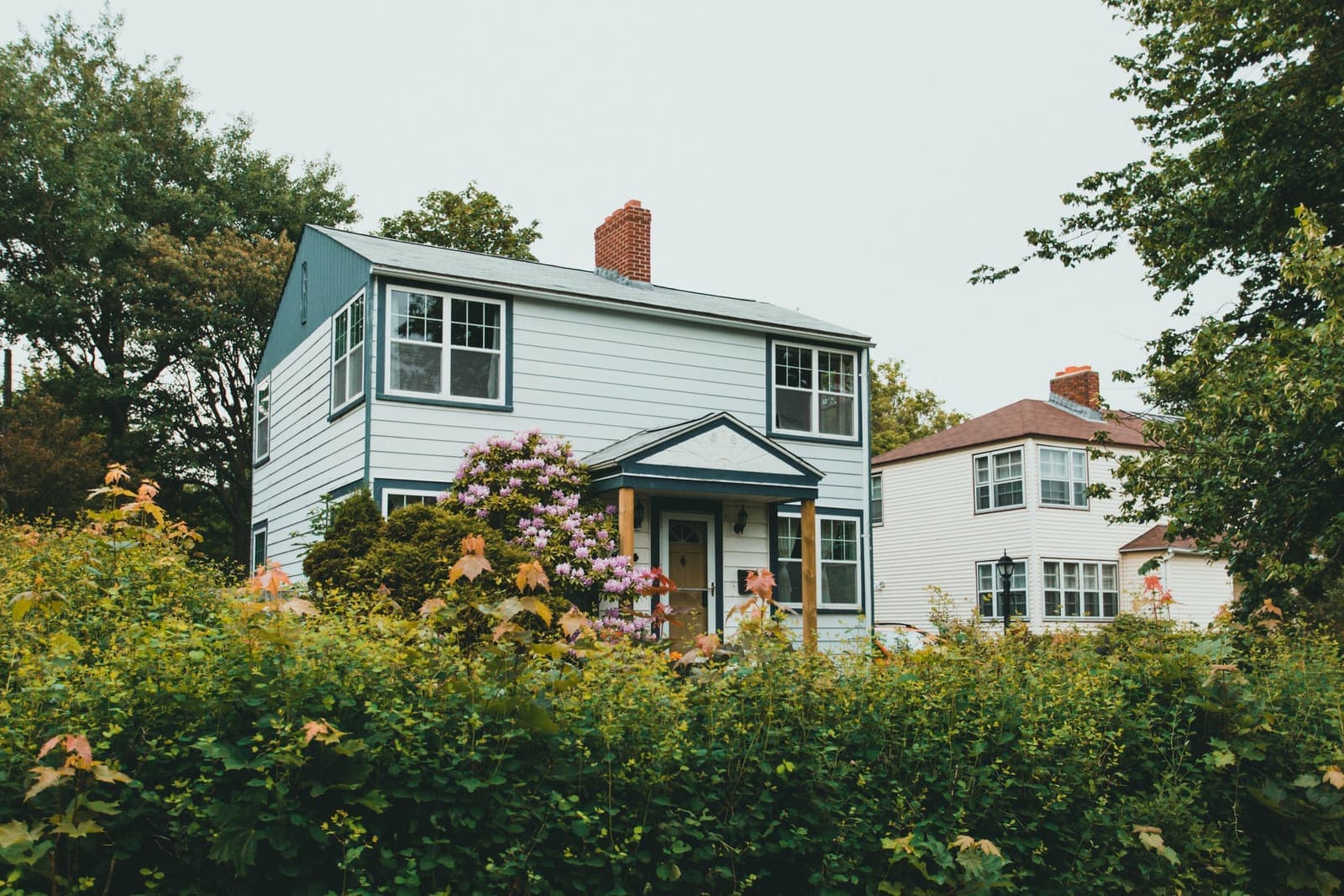 Two-story house behind a hedge on a leafy street, the kind of home movers in East Providence, RI handle every week